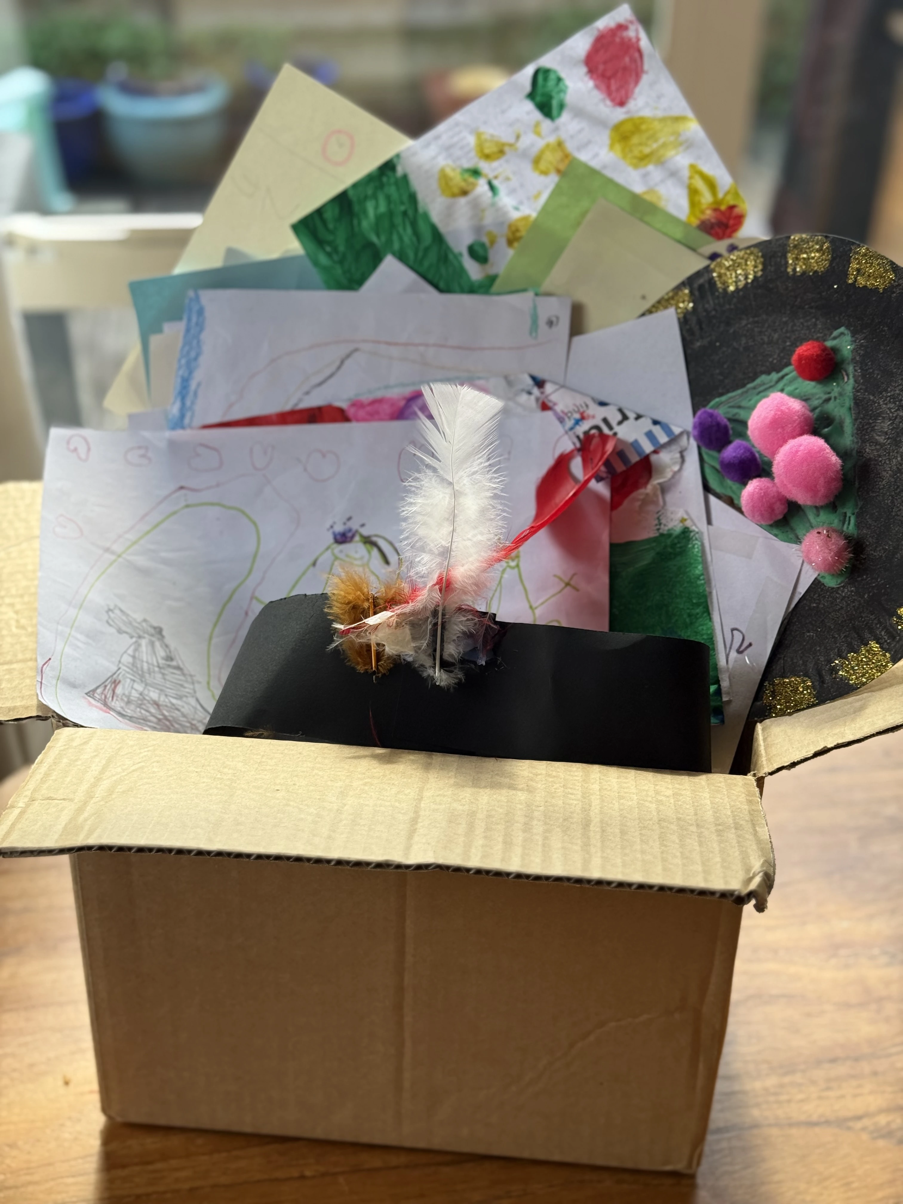 A collection of children's artwork being sorted and organised at home